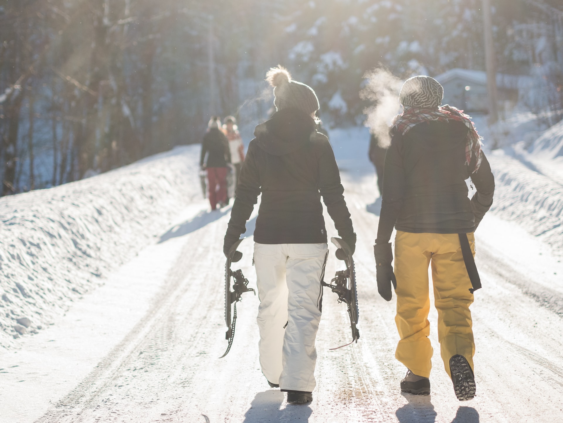 Two people walking to the slopes with their gear on a cold day; their breathe is visible.
