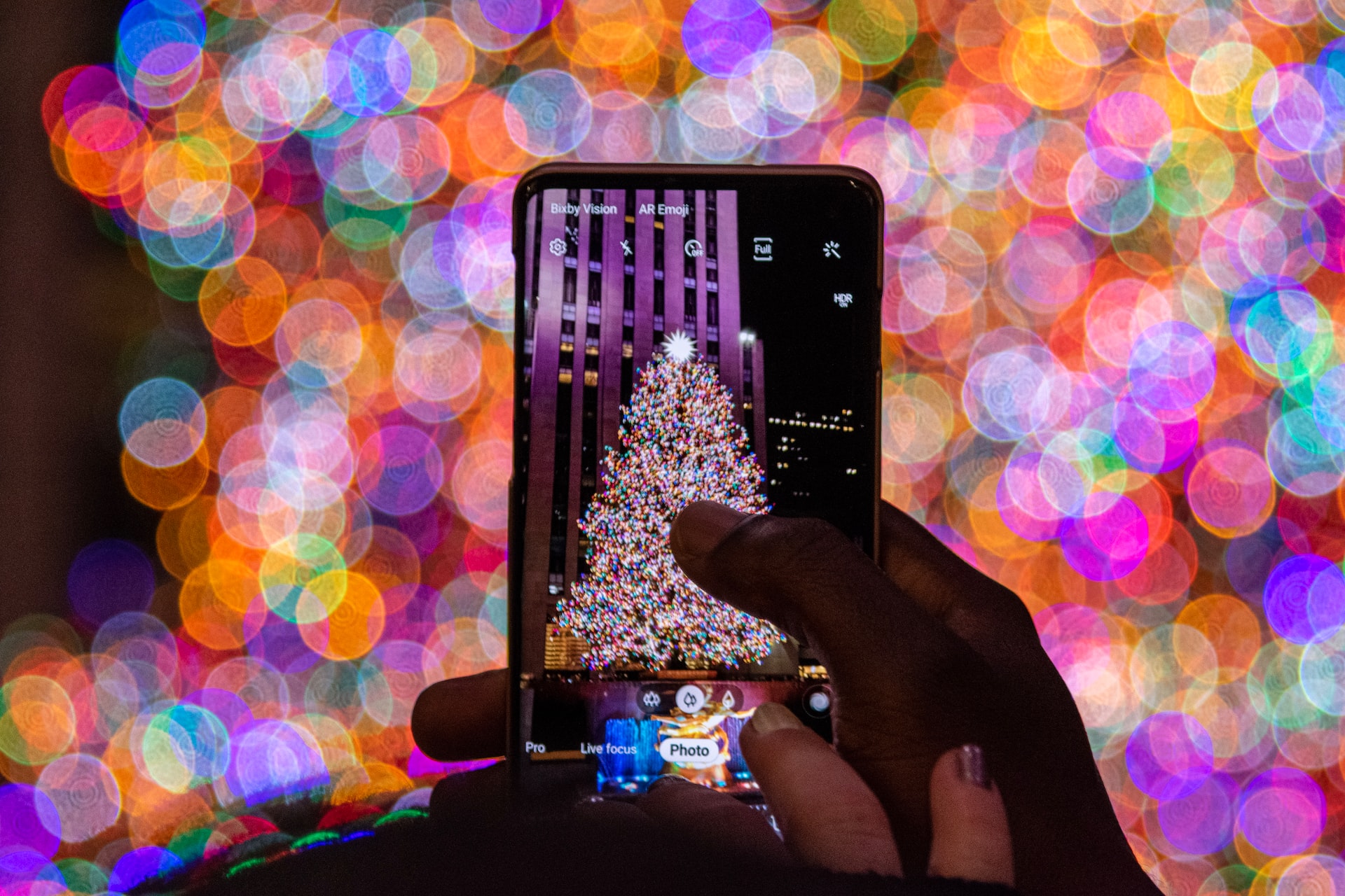 A person taking a photo on their phone of the Rockefeller Christmas Tree.