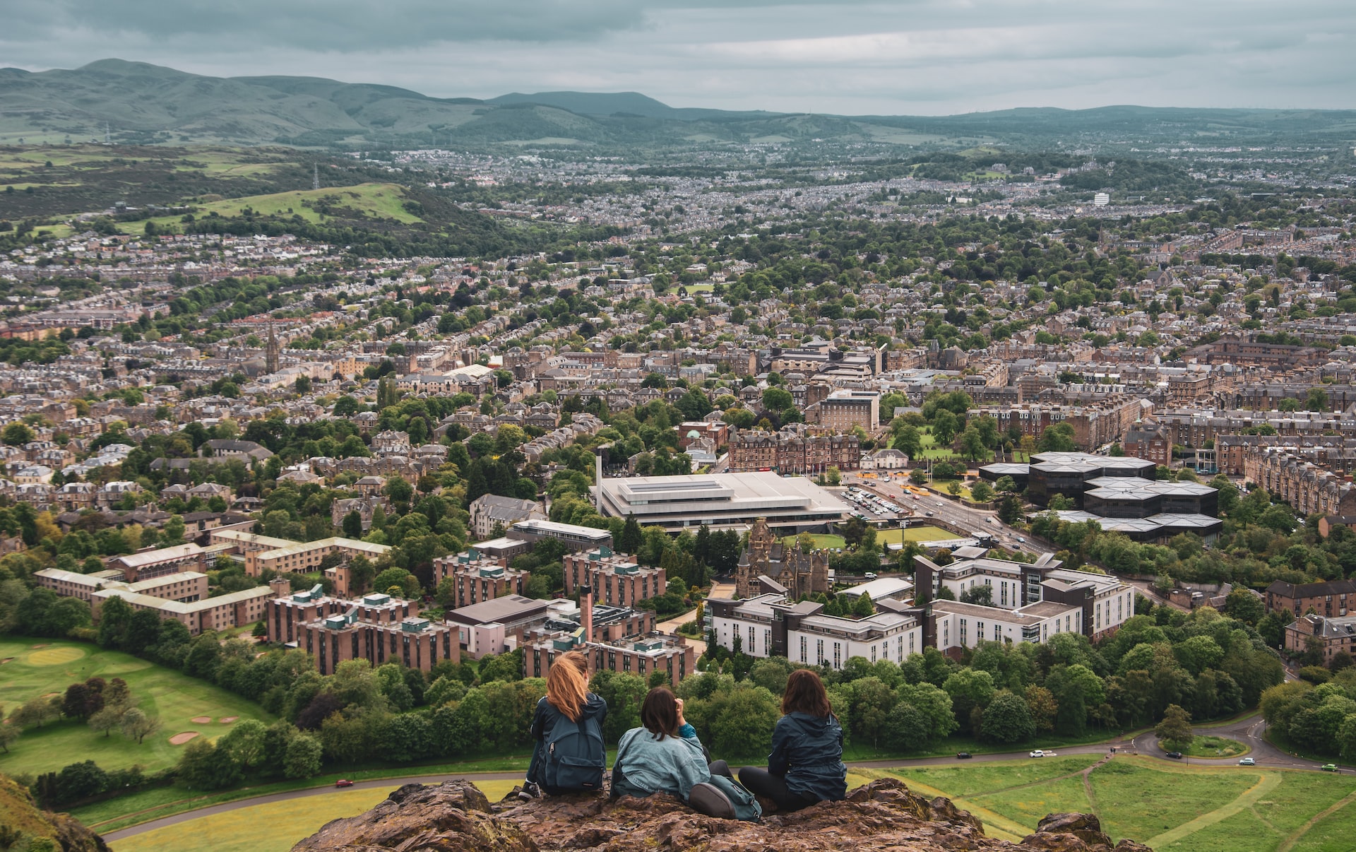 Three friends looking down on the city of Edinburgh from Arthur's Seat.