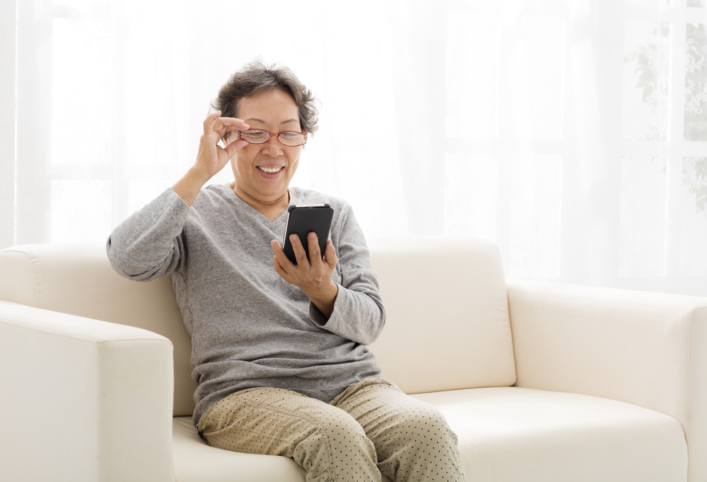 Senior woman smiling while using her phone.