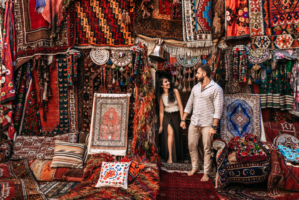 Man and woman holding hands standing in an Oriental carpet store.