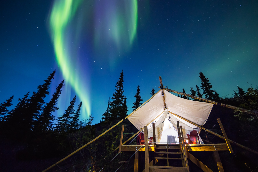 A glamping tent pitched under the aurora borealis.
