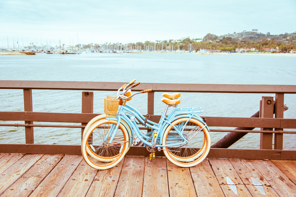 Twin retro bicycles parked on a pier beside a bay.