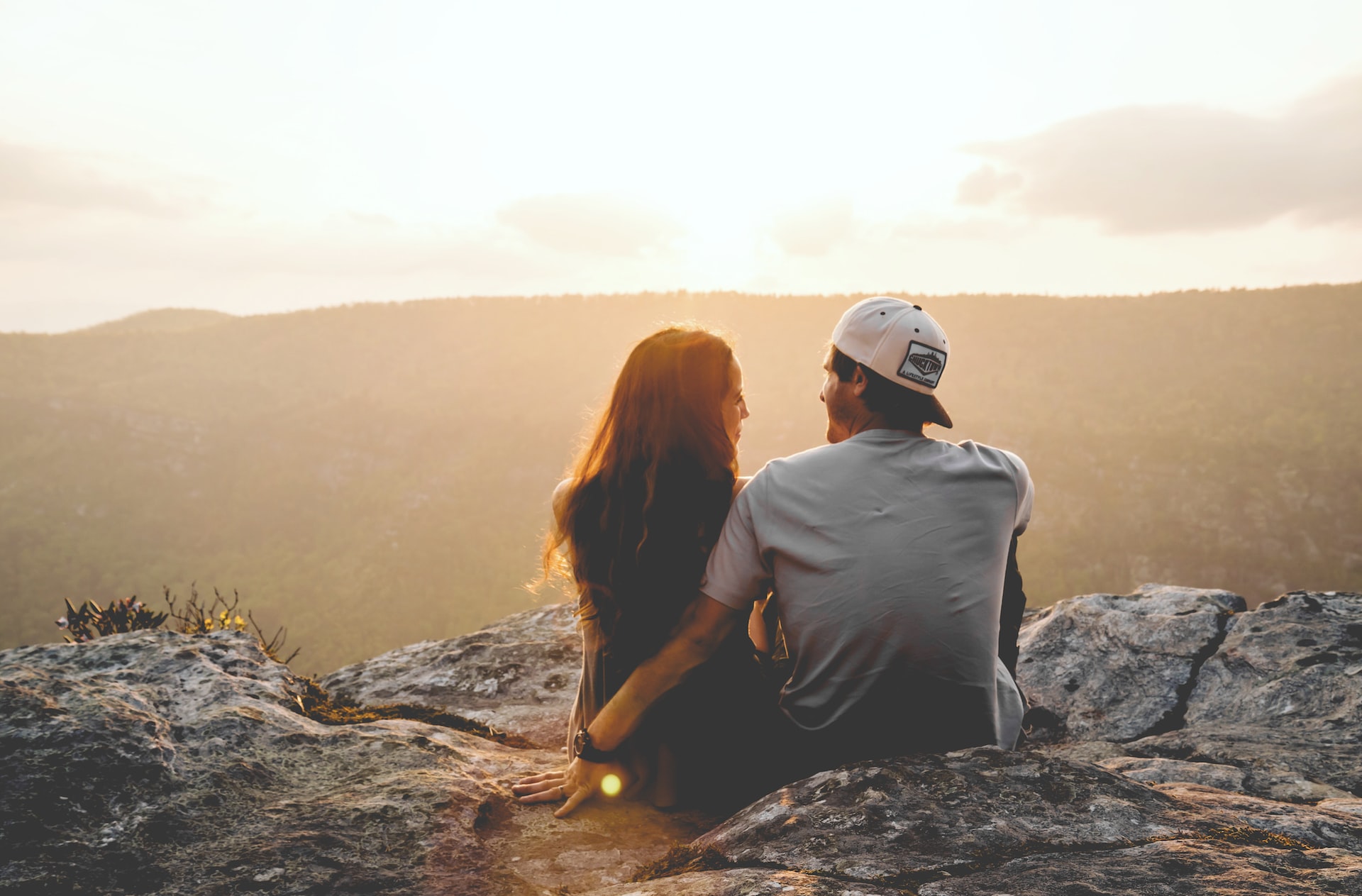A couple sitting together on a mountain top.