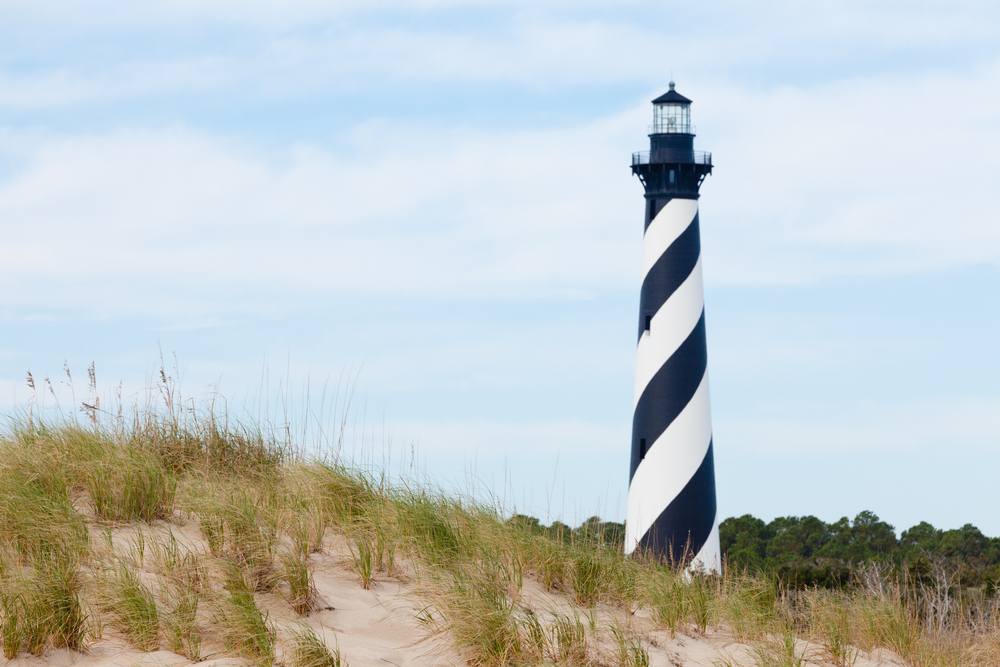 Cape Hatteras Lighthouse towers over beach dunes of Outer Banks island near Buxton, North Carolina, US.