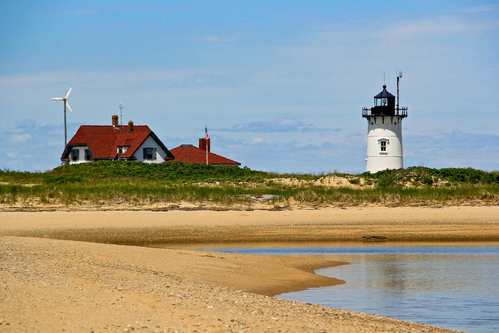The Race Point Lighthouse at low-tide rising above a sandy beach.