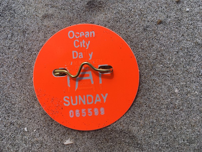 Close-up photo of an orange beach tag on the sand associated with Ocean City.