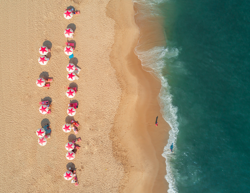 Aerial view of the beach in Cape May with white umbrellas with red stars on the top.