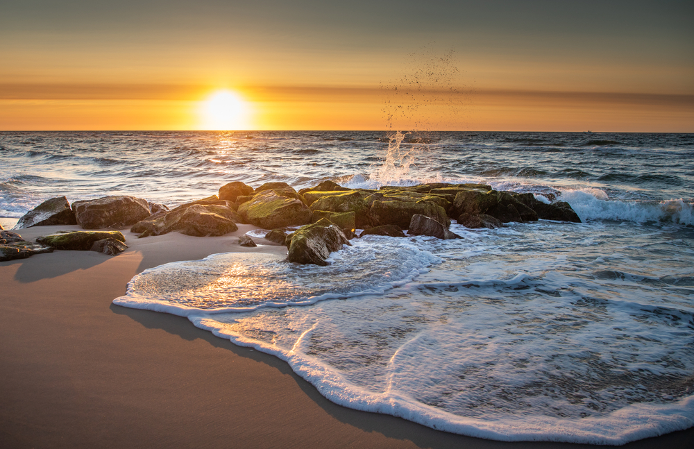 Waves at sunset washing over a series of rocks on the New Jersey coastline.