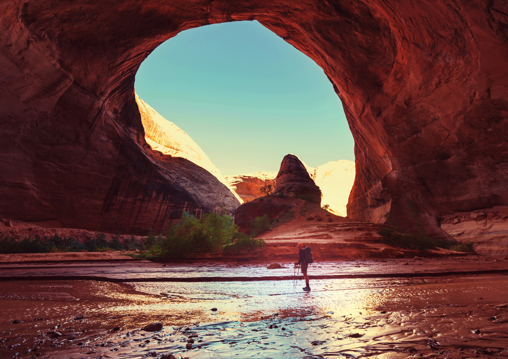 Hiker standing in Coyote Gulch rock formation in the rugged, desolate paradise of Grand Staircase-Escalante National Monument.