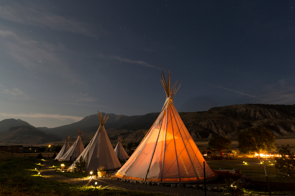 Tipis at night glowing brightly from the inside at Yellowstone National Park.