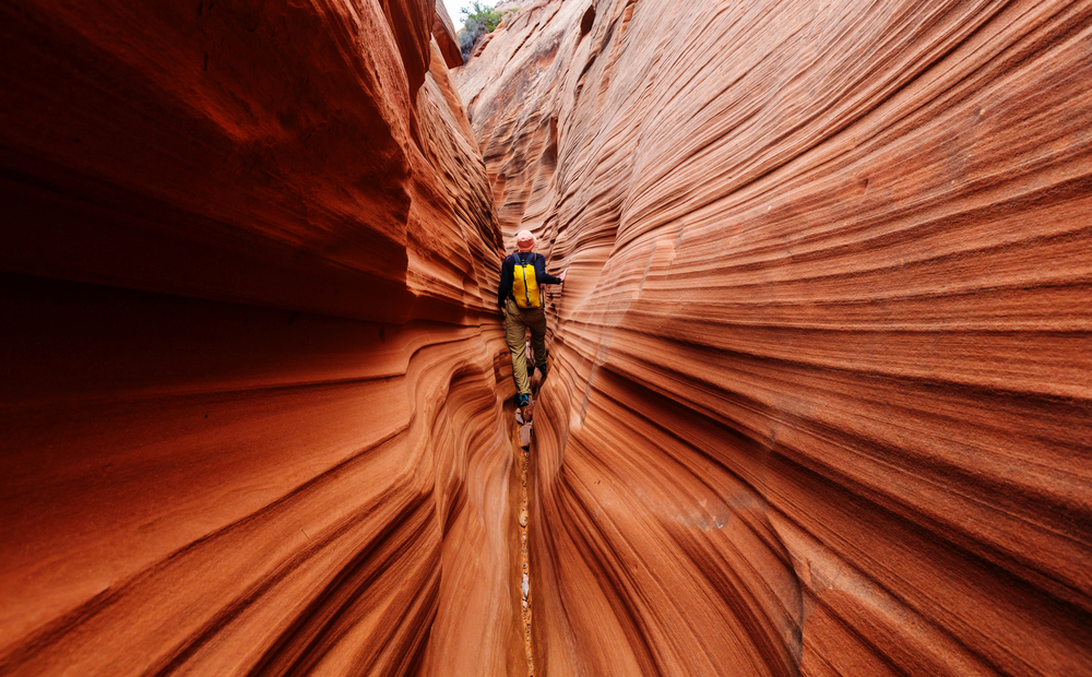 A woman squeezing through Slot Canyon in Grand Staircase-Escalante National Monument. 