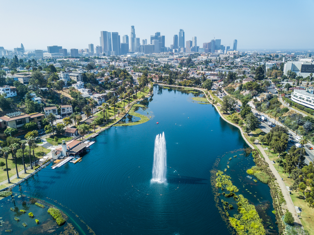 An aerial shot of Echo Park and the surrounding greenery with downtown Los Angeles in the distance on a bluebird day in California.