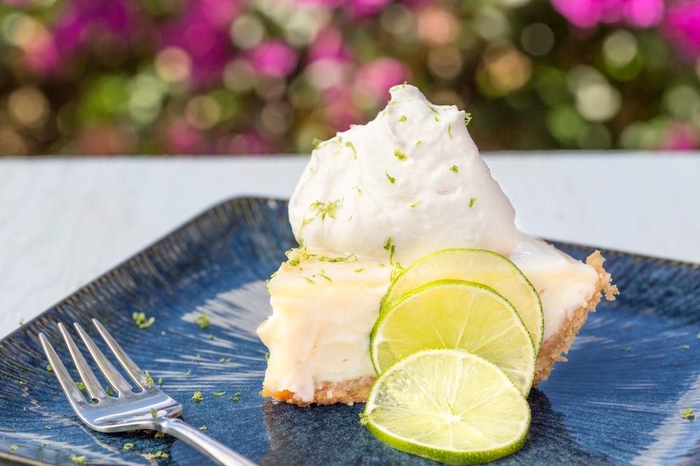 A slice of Key lime pie served with whipped cream and lime zest.