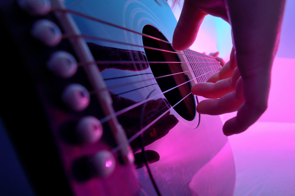 Closeup of an acoustic guitar played by a girl.
