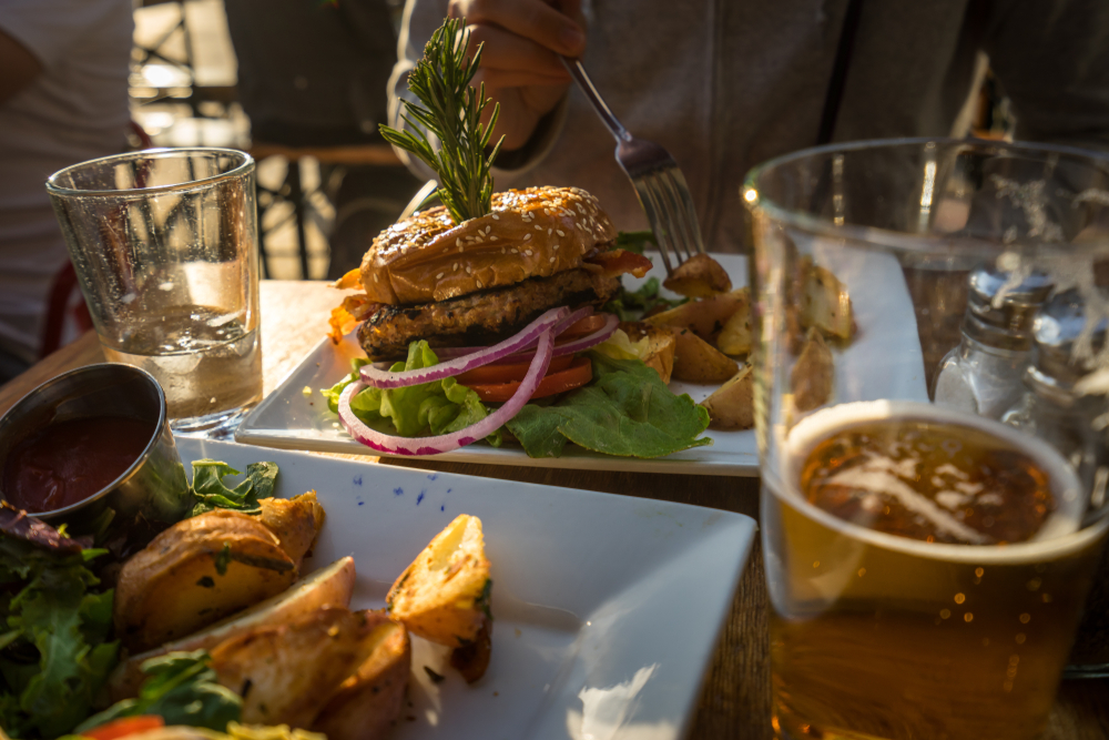 People enjoying a hamburger and beer while eating outside on a summer evening in Los Angeles.