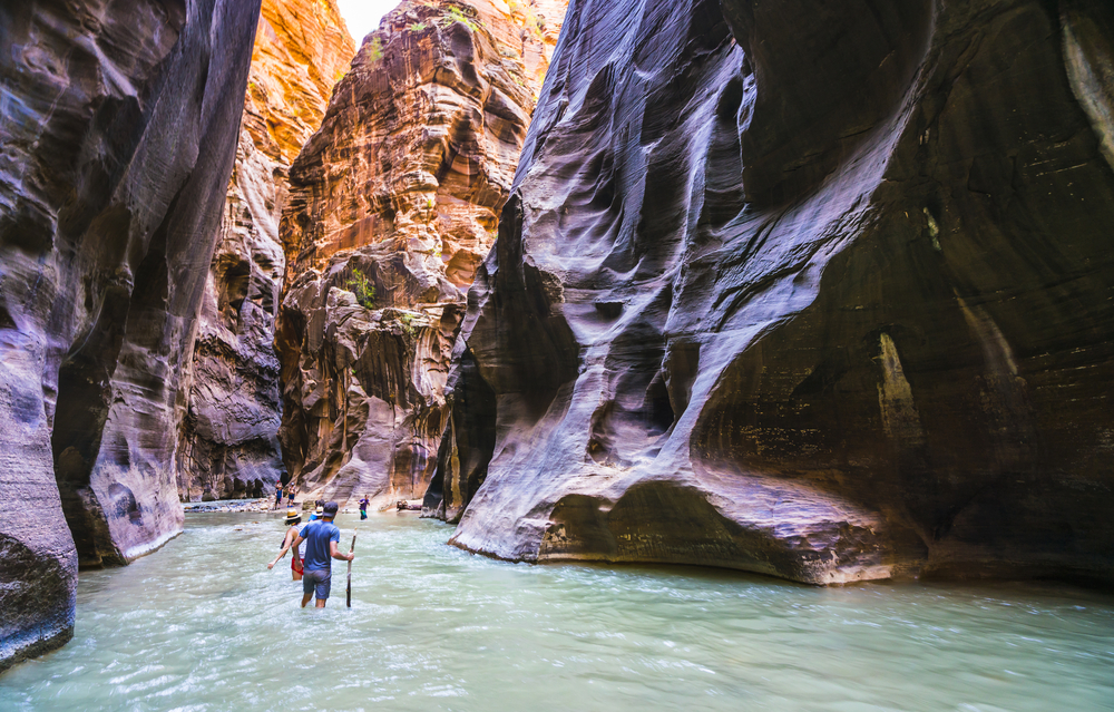 People hiking in The Narrows along Virgin River in summer season, Zion National Park, Utah, USA.