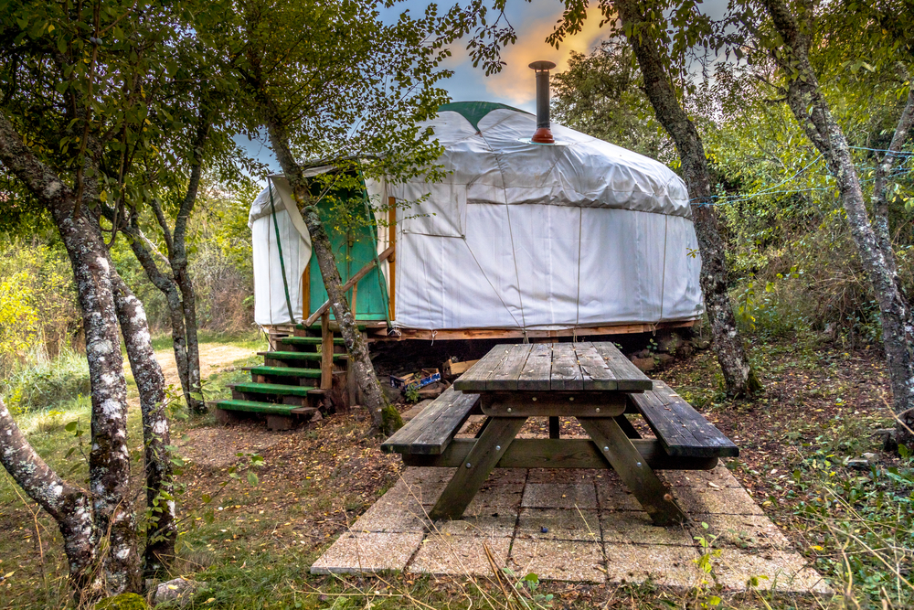 A traditional Mongolian yurt next to a picnic table.