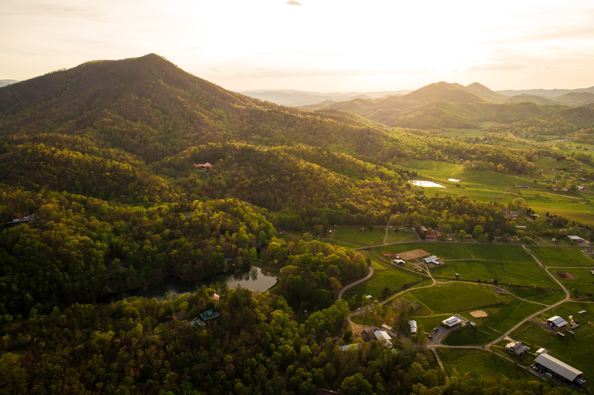 Forests and green mountains with farm lands and buildings interspersed between them.