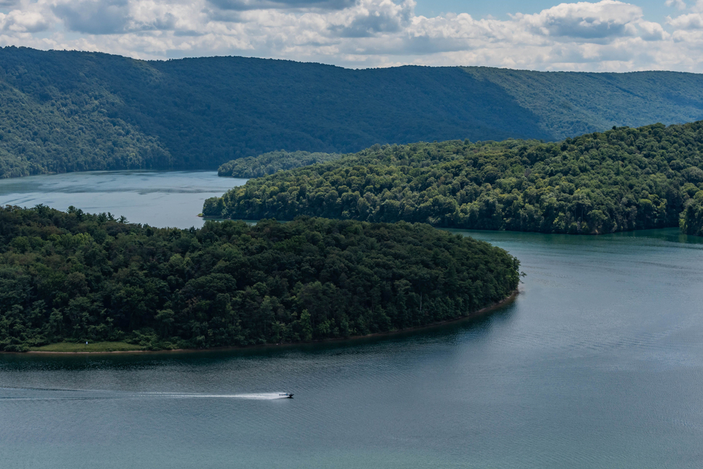 A bird's eye view of Raystown Lake and a boat cruising along the calm water.