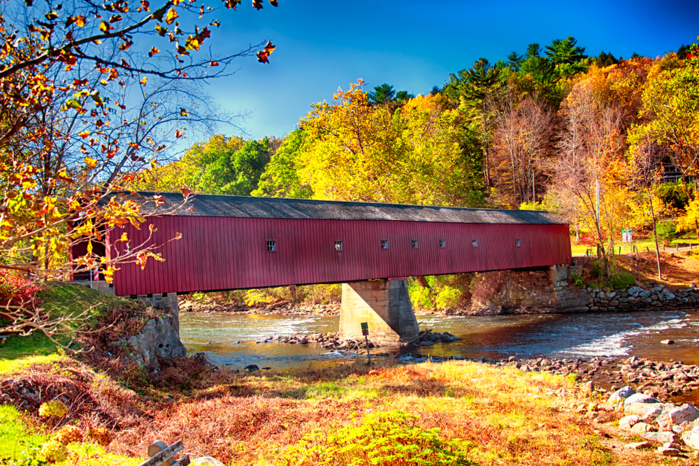 An iconic west cornwall covered bridge spanning the Houstanic River in Connecticut during autumn in New England.
