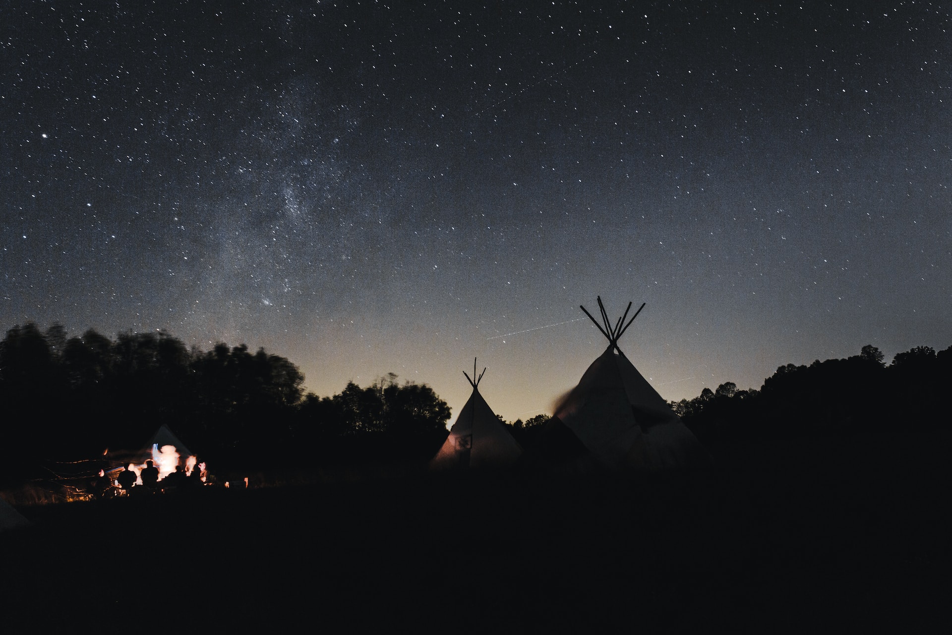 Two tipis in the dark with people by a far close by in North Carolina.