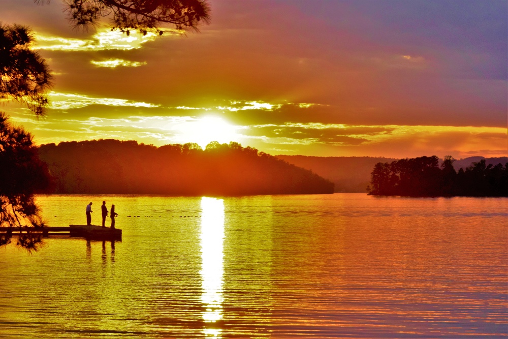People fishing from a dock at sunset on Lake Guntersville, Alabama.