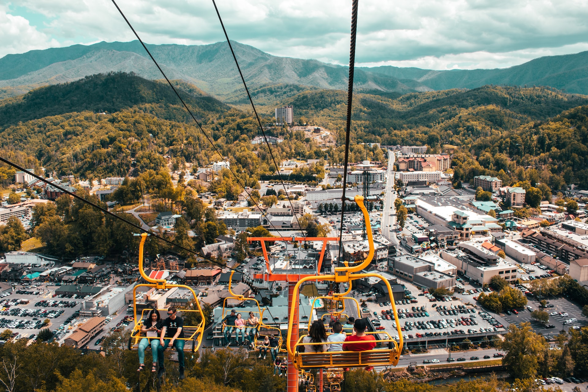 Couples and families riding the chairlift with views of the Smoky Mountains and Pigeon Forge behind them.