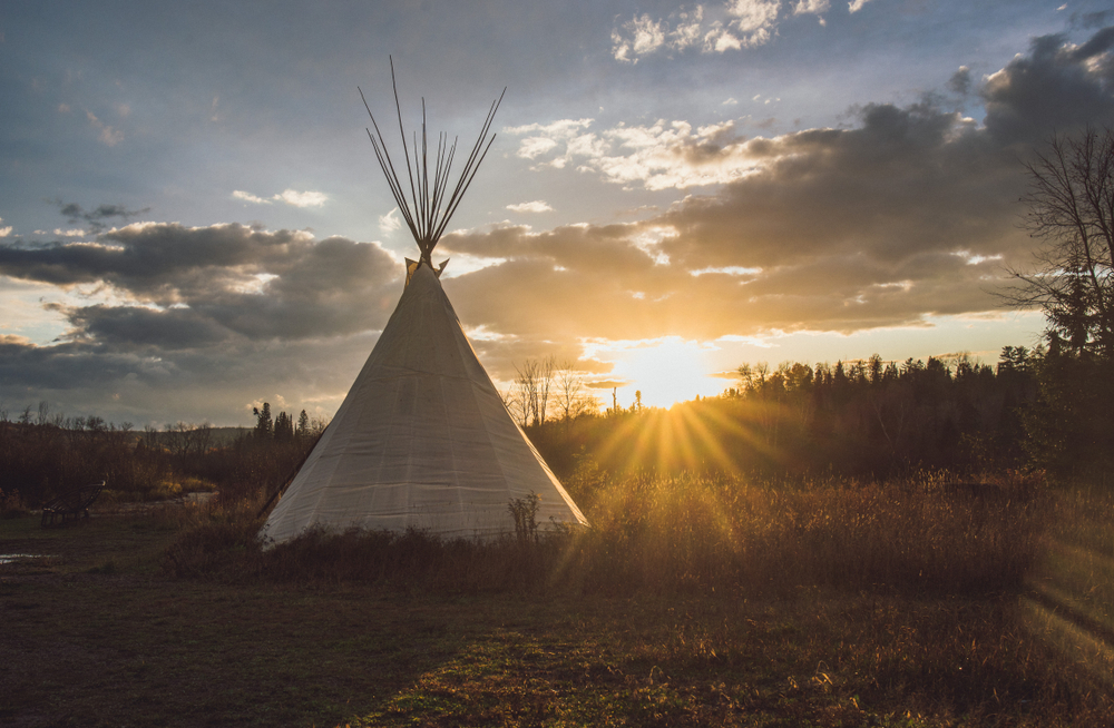 Tipi at sunset framed by a dramatic sky.