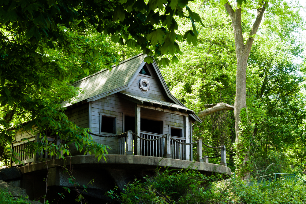 An elaborate treehouse with balcony in the middle of the woods.