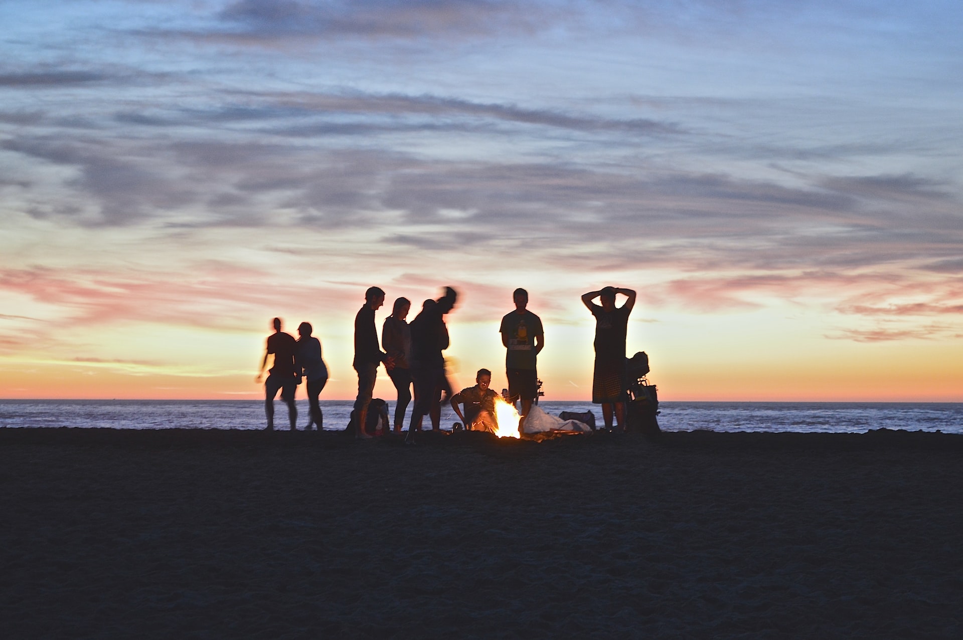 Friends hanging out around a campfire on the beach.