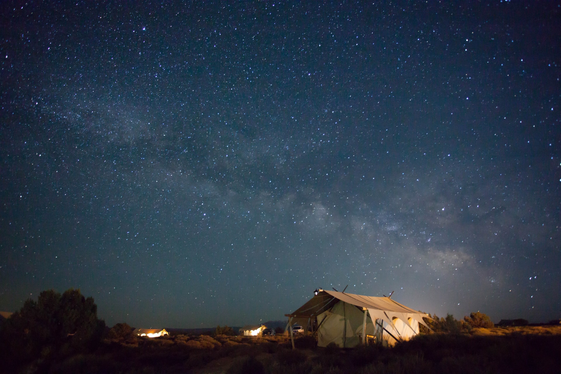 An Under Canvas glamping tent under an overwhelmingly bright night sky full of stars.