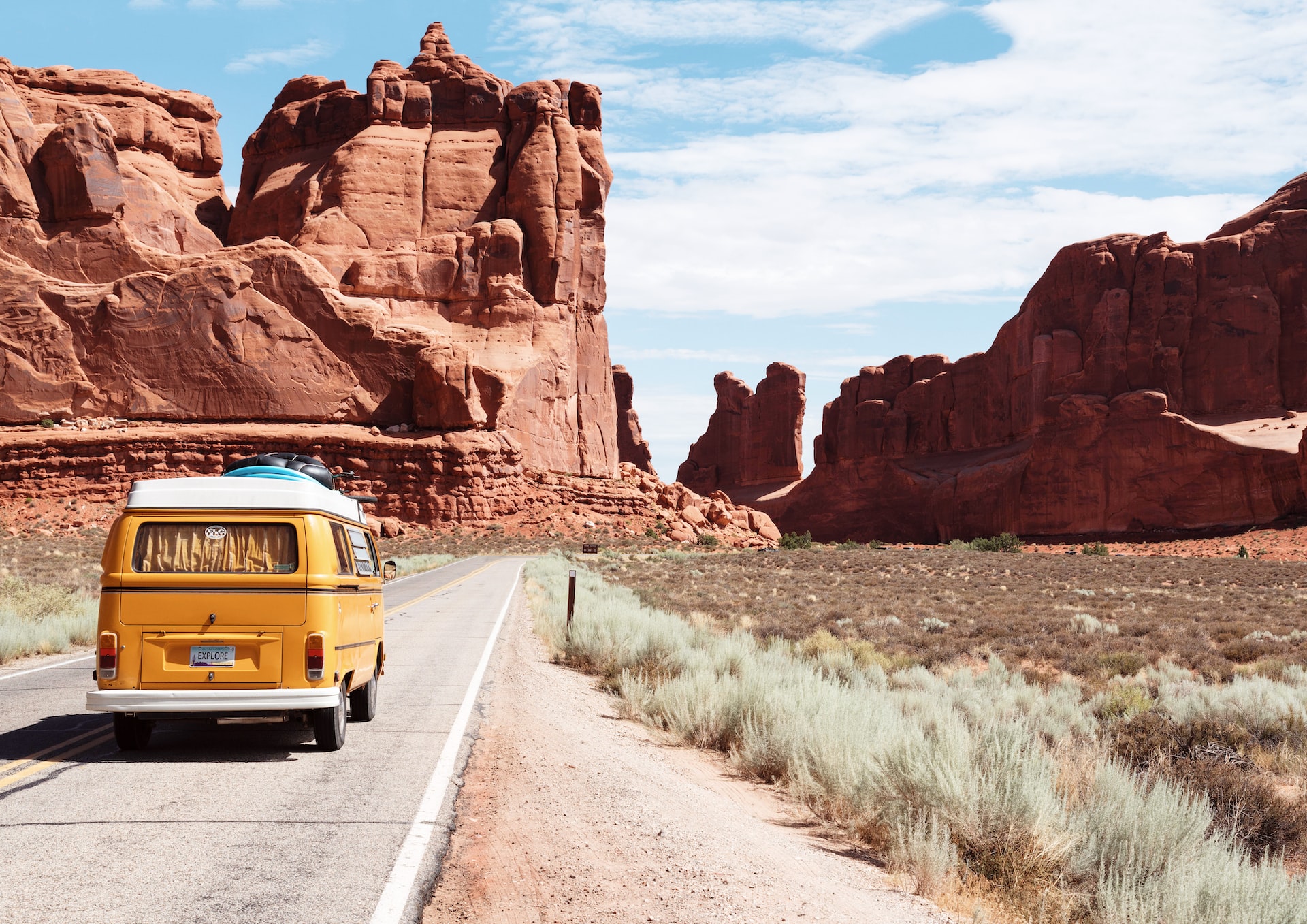 A yellow van driving through red rock formations in Moab.