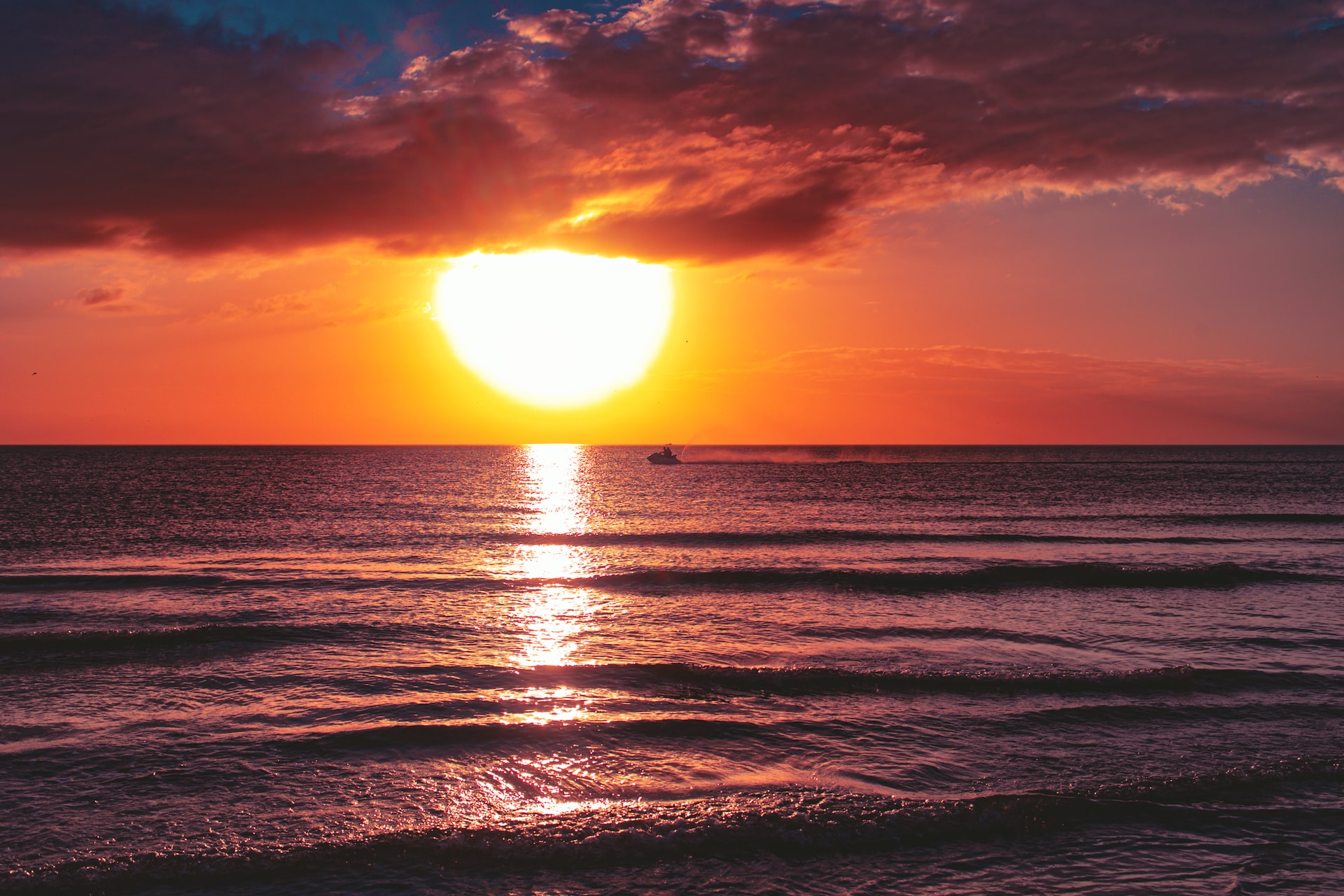 Dark sea under cloudy sky during golden hour at the beach.