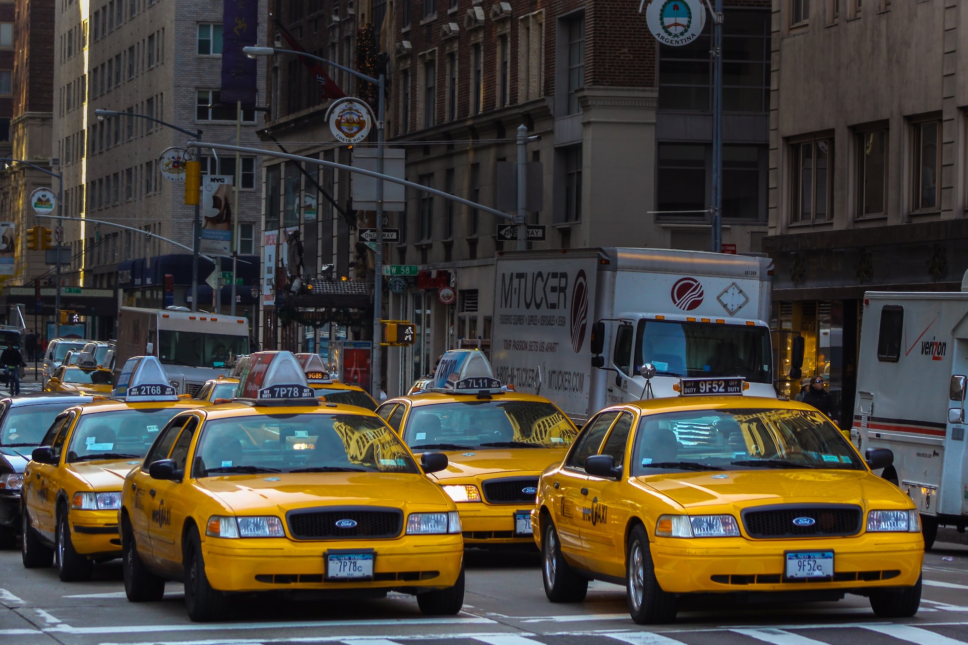 Four yellow taxis in New York City, stationary at a pedestrian crossing.
