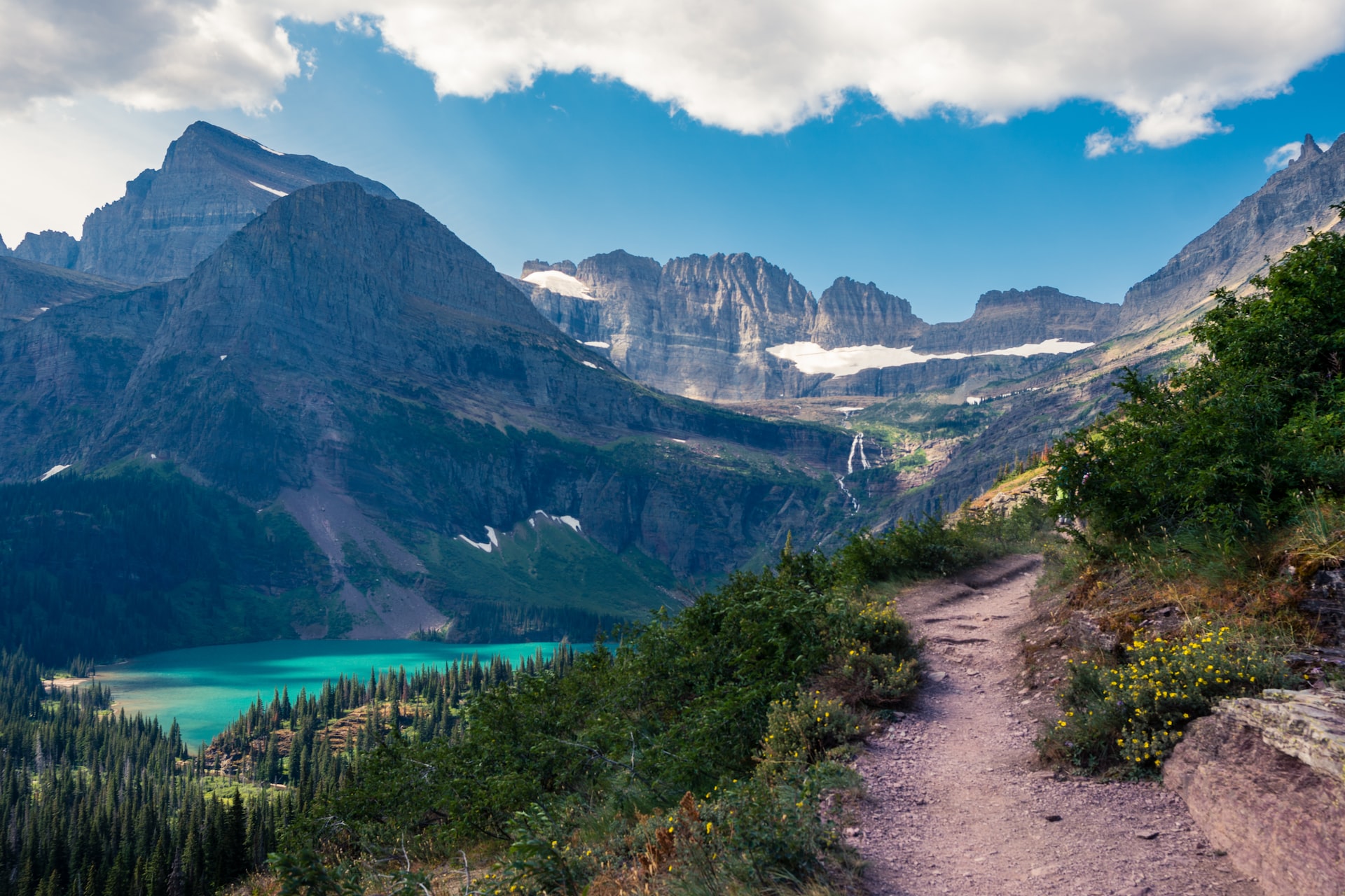 The Grinnell Glacier Hike takes you above the treeline and up to the mountains with turquoise water in a lake below.