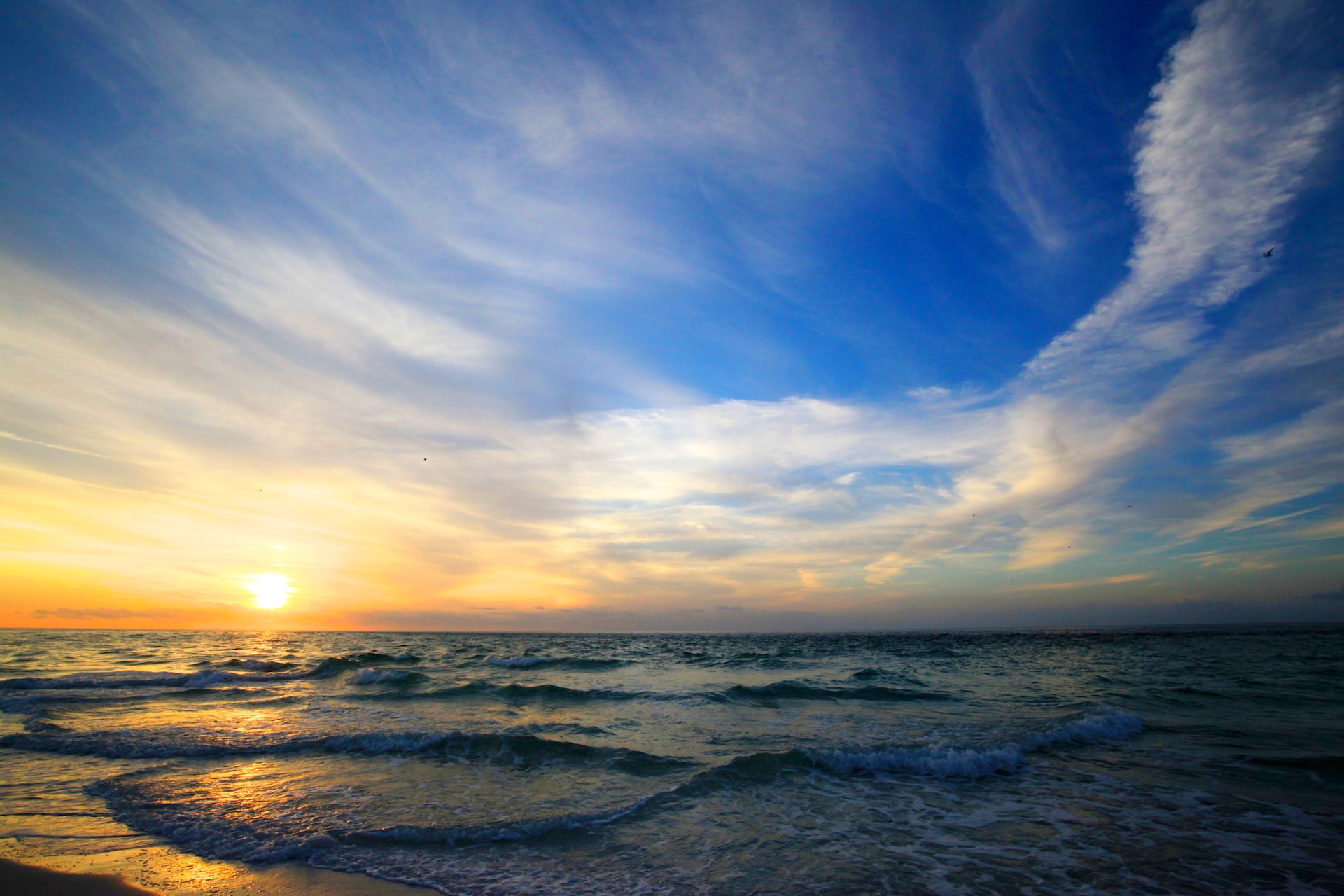 The setting sun on waves along the beach.