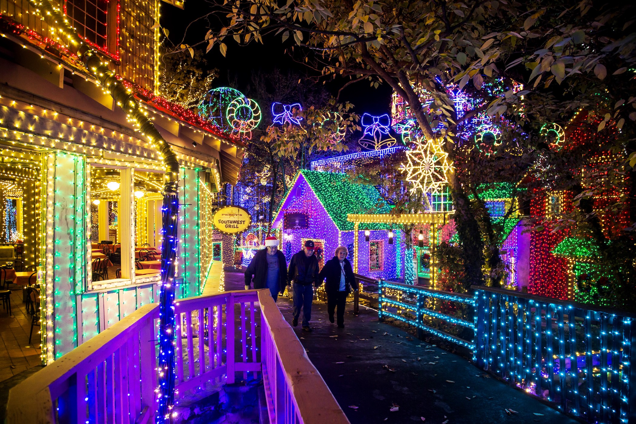 Three older folks walking along a colorfully lit scene.