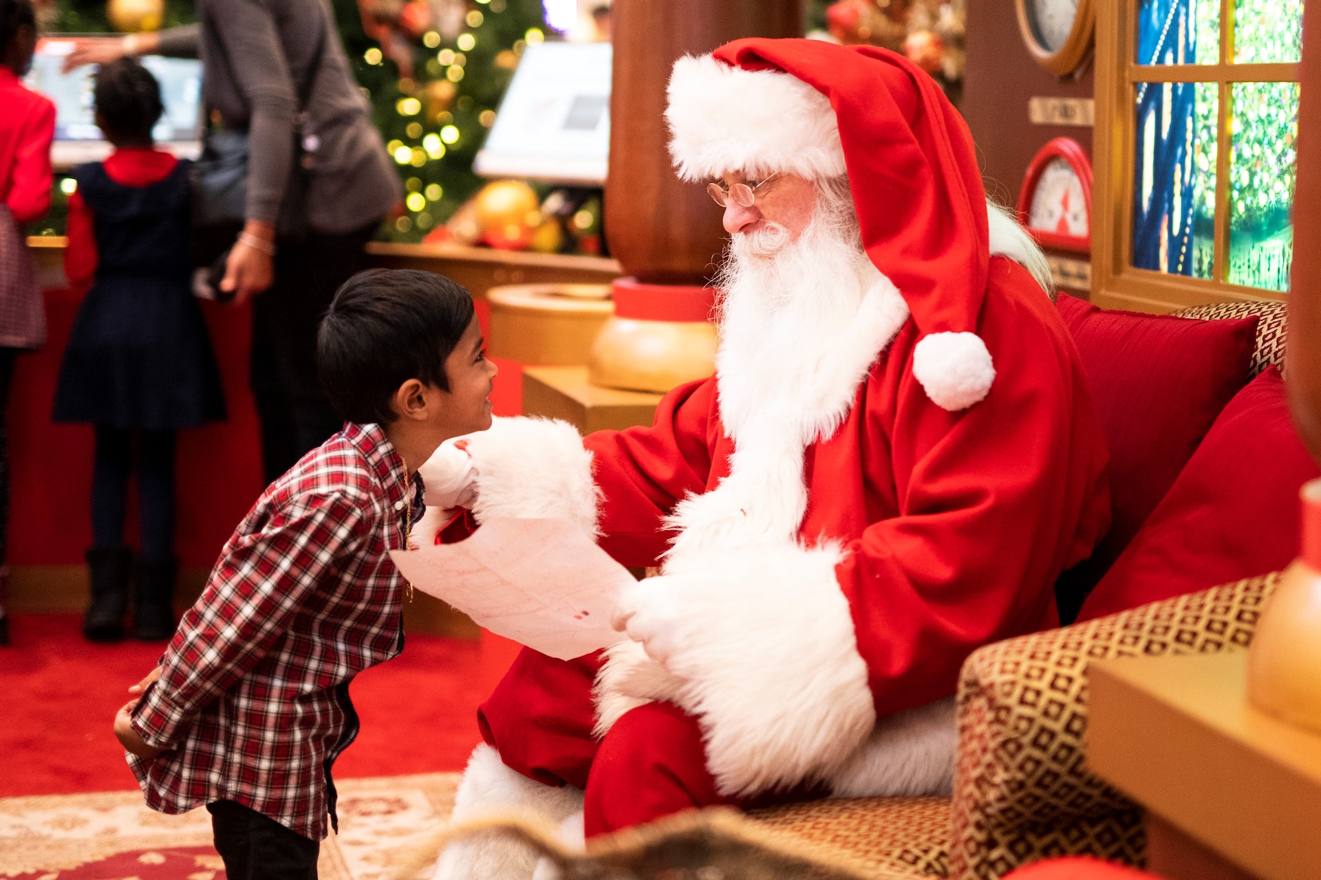 A boy standing in front of Santa Claus during a holiday festival.
