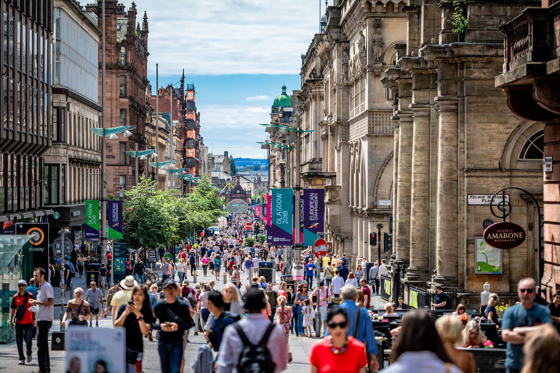 Sunny day on Glasgow's Buchanan Street, full of shops and people walking around.