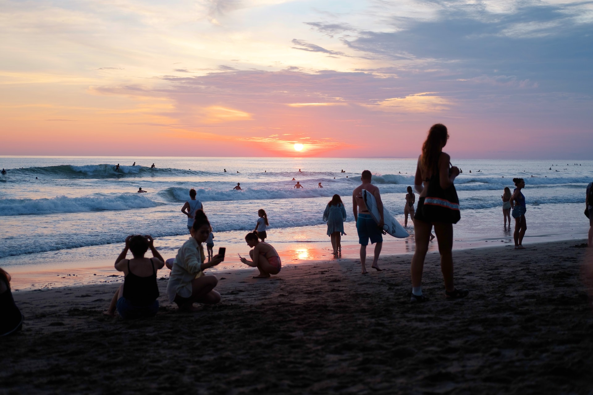 People on the beach in Bali surfing and walking along the shore.