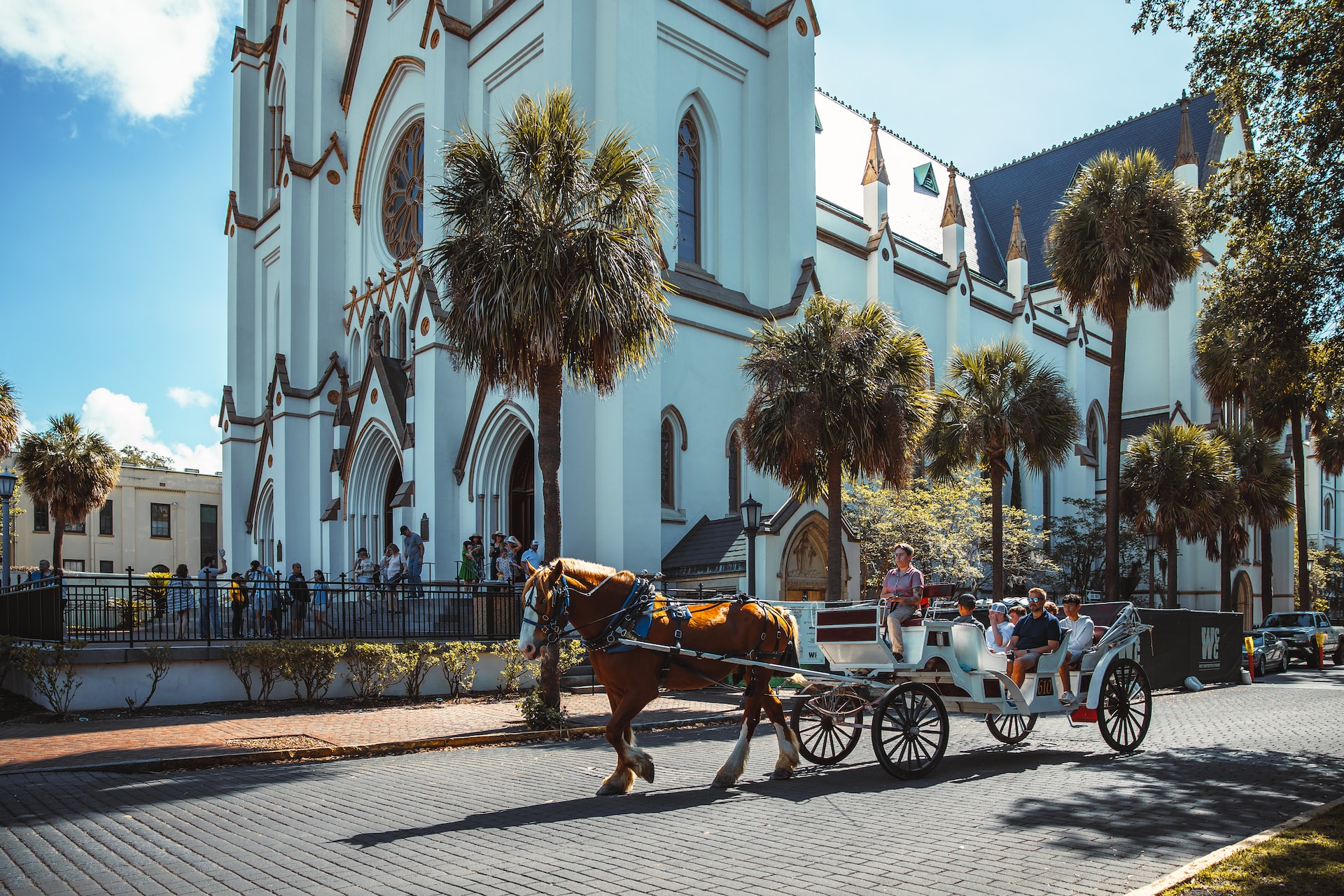 A horse and carriage walking beside an ornate church in Savannah.
