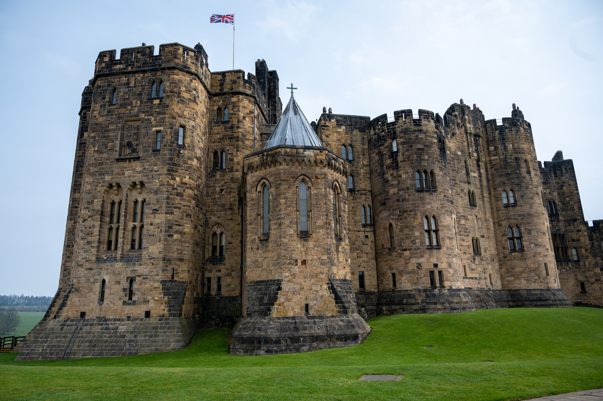 Alnwick Castle with a British Jack flag flying high over the ramparts.
