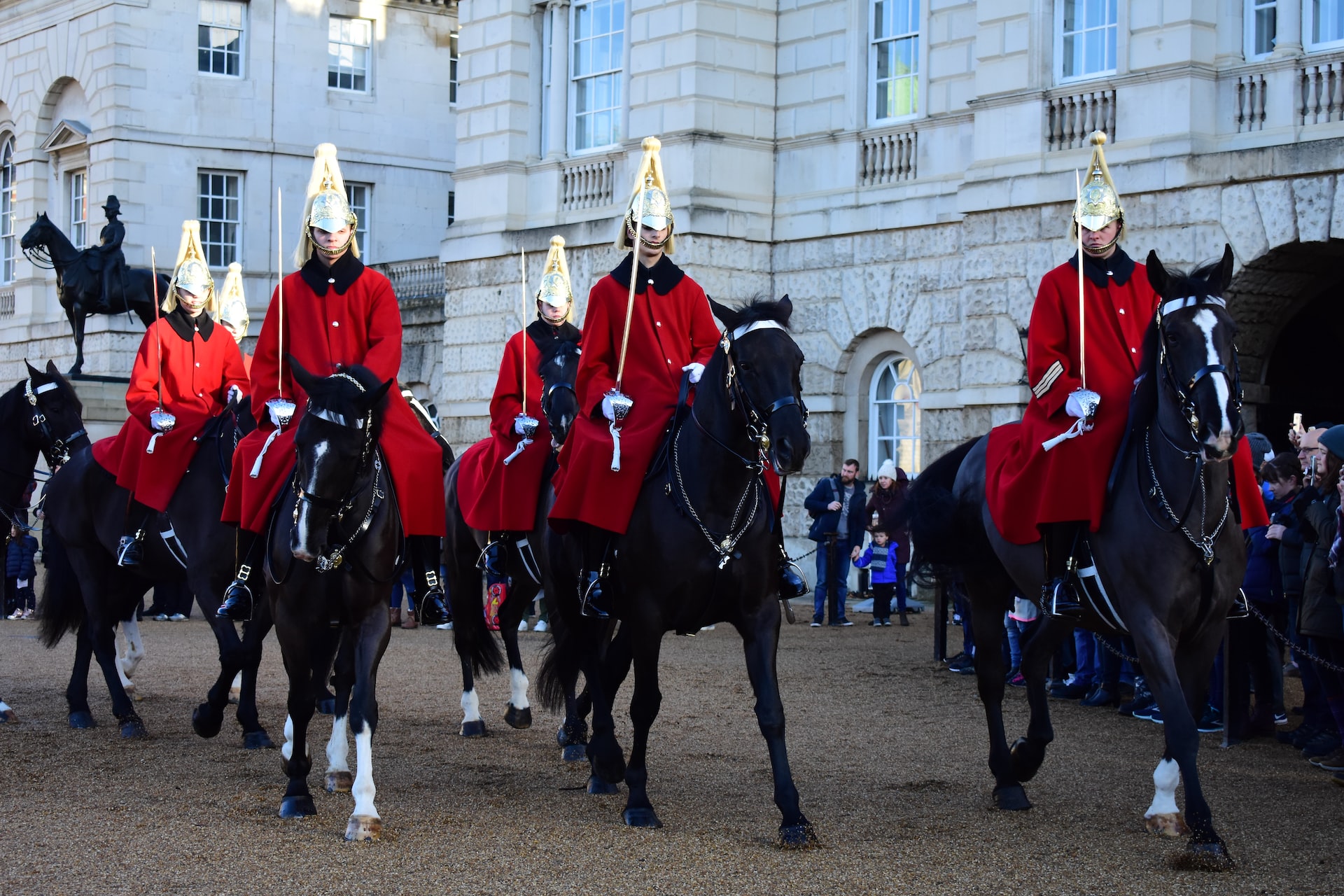 Guards mounted on horseback wearing traditional garb in front of Buckingham Palace.