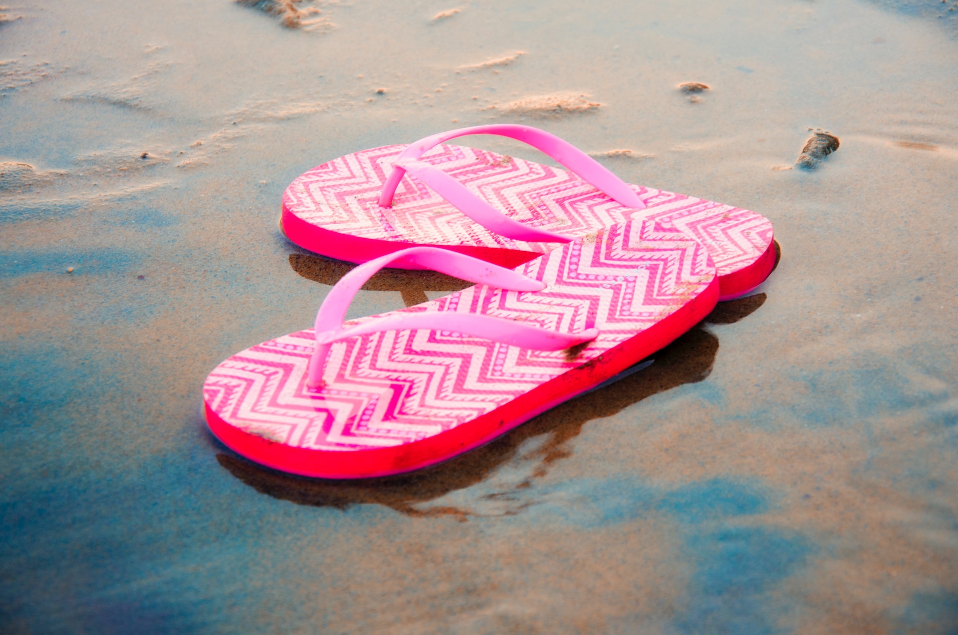 Electric pink flip flops along the beach.