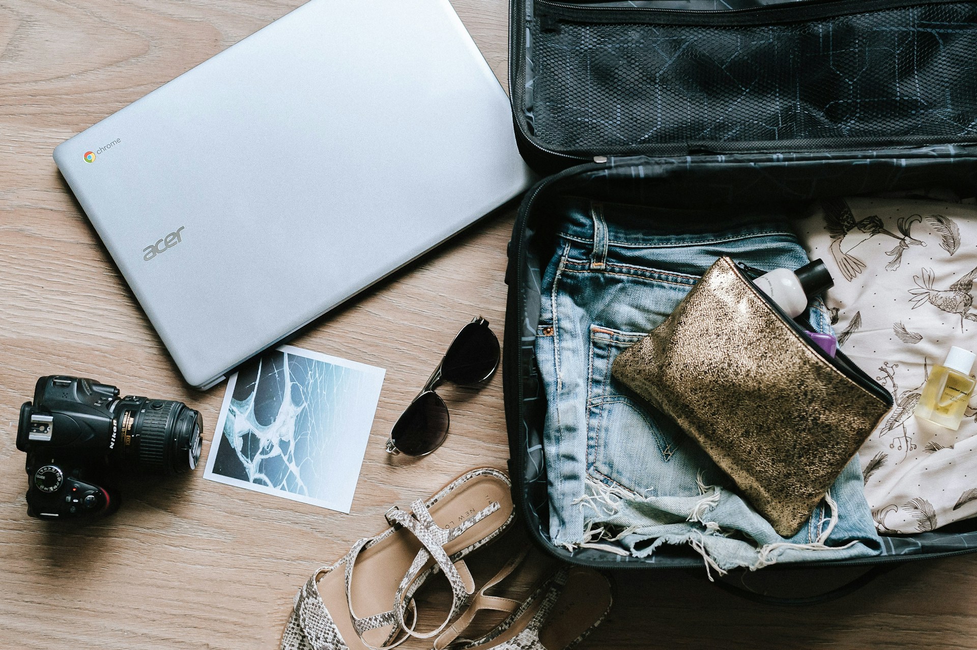 Black sunglasses and a laptop being packed into a suitcase.
